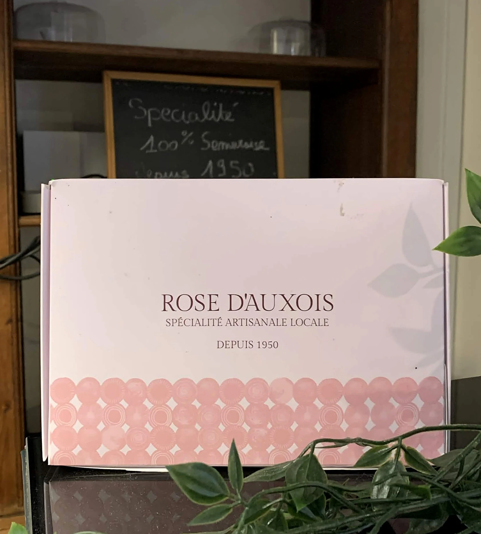 La boîte Rose d'Auxois devant l'ardoise « Spécialité 100 % Semuroise depuis 1950 » à la pâtisserie